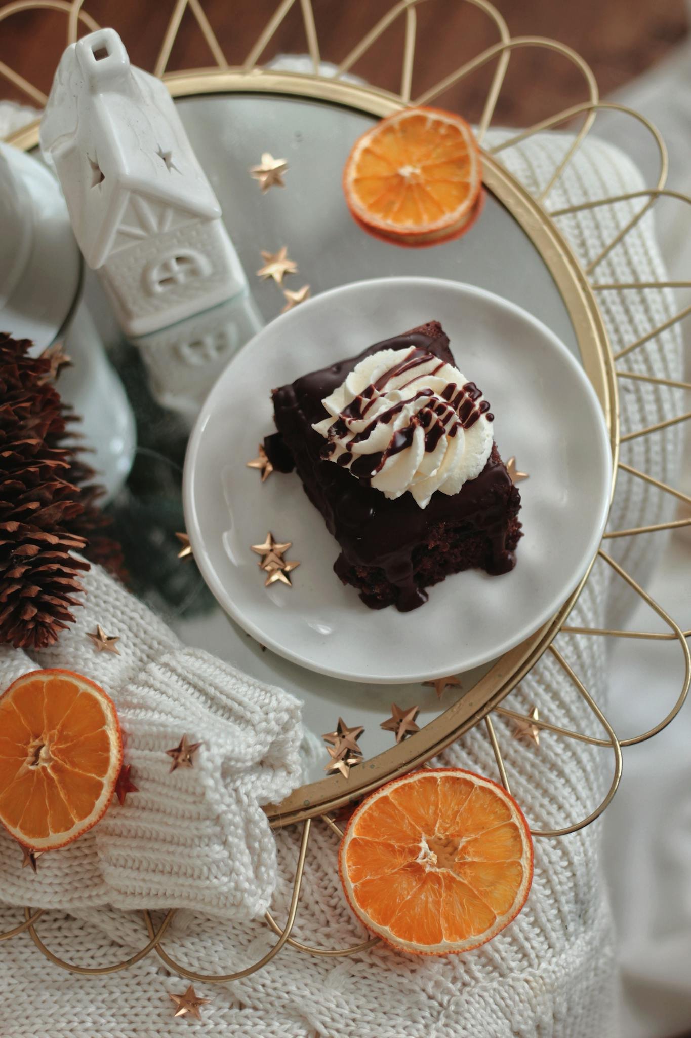 Top view of a chocolate cake with whipped cream, surrounded by dried orange slices and festive decor.